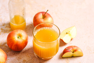 Ein Glas frischer Apfelsaft und rote Äpfel auf einem rosa Tisch. Herbst, Erfrischungsgetränk.