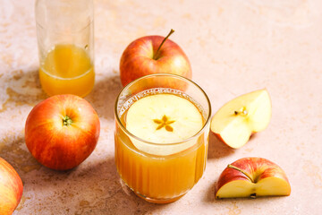Ein Glas mit frischen Apfelsaft und rote Äpfel auf einem rosa Tisch. Herbst, Erfrischung.