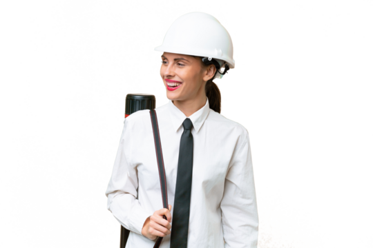 Young architect woman with helmet and holding blueprints over isolated background looking to the side and smiling - Powered by Adobe