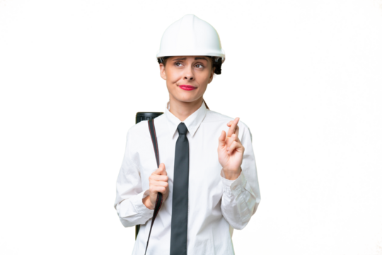 Young architect woman with helmet and holding blueprints over isolated background with fingers crossing and wishing the best