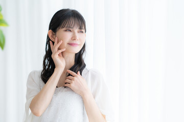 リビングでスキンケアをするミドルの女性