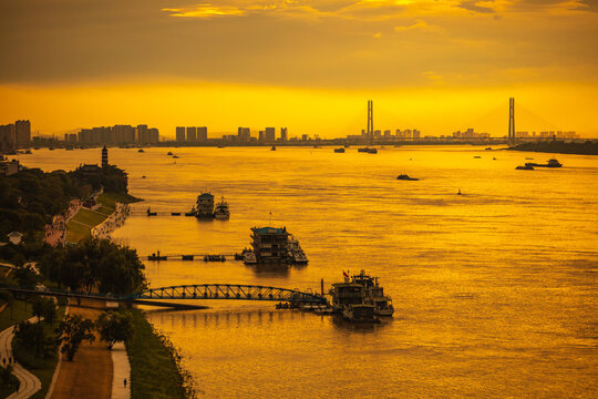 The Yangtze River and its shipping vessels, bathed in the glow of the setting sun, are located in Jiujiang, a historical and cultural ancient city in eastern Asia, Jiangxi Province, China.