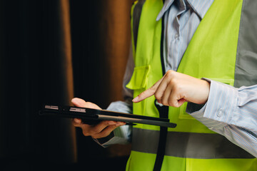 Professional Person in Safety Vest Using Tablet for Work Site Management and Communication with Focus on Technology and Safety
