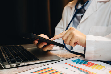 Doctor using tablet and laptop for medical analysis and data monitoring in modern healthcare environment at office desk