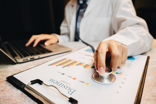 Business analysis with medical interpretation concept using stethoscope and charts on desk with laptop background in office setting