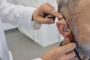 Audiologist customizes a hearing aid to improve an individual's audio experience with advanced techniques, close-up. Real ear measurements