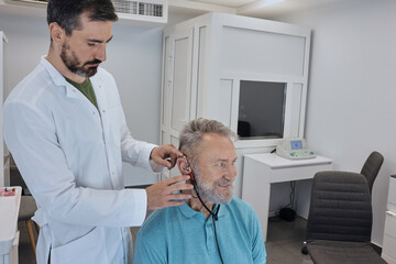 Audiology. Specialized audiological equipment is being used to adjust a hearing aid for an individual during a fitting session