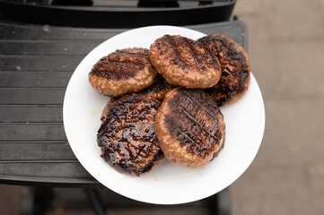 Grilled beef burgers on white plate outdoors