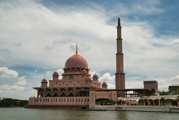 Obraz premium Minaret and dome at Putra Mosque, the main mosque in Putrajaya, the administrative capital of Malaysia. The mosque is pink in color and is located on the shores of Putrajaya's artificial lake.
