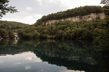 A rocky cliff is reflected in a clear mountain lake