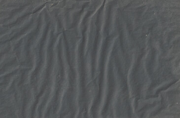 Black crumpled paper texture with folds, black background