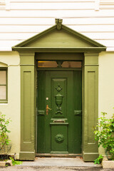 Ornate green wooden door on an older building providing an entrance, Bergen, Norway.
