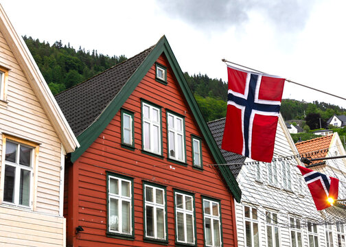 Traditional wooden houses of Bryggen, Bergen displaying Norwegian flags against a cloudy sky