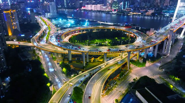 Aerial view of the illuminated Nanpu Bridge at night, a multi-level highway interchange with heavy traffic, connecting urban districts of Shanghai, China.