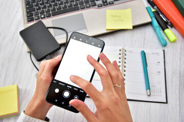 Closeup female hands holding a mobile phone with blank screen in an office environment