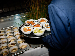 Service traiteur lors d’une soirée d’entreprise sur un rooftop à Paris, assiettes gastronomiques de truffe, risotto et aiguillettes panées servies avec élégance.