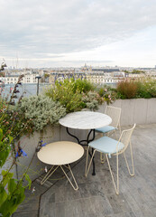 Terrasse végétalisée sur un rooftop parisien au coucher du soleil, vue sur les toits et monuments de Paris, ambiance élégante et conviviale d’une soirée d’entreprise en plein air.