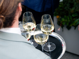 Verres de vin blanc servis sur un plateau argenté lors d’une soirée d’entreprise sur un rooftop à Paris, ambiance élégante et conviviale entre collègues.