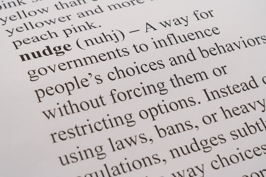 A dictionary mockup on paper of current buzz word Nudge with respect to governmental guidance with selective focussing