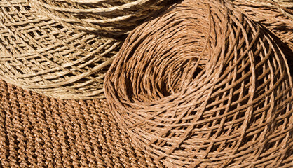 Natural raffia fibers are wound into spools against a crocheted background.