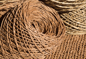 Natural raffia fibers are wound into spools against a crocheted background.