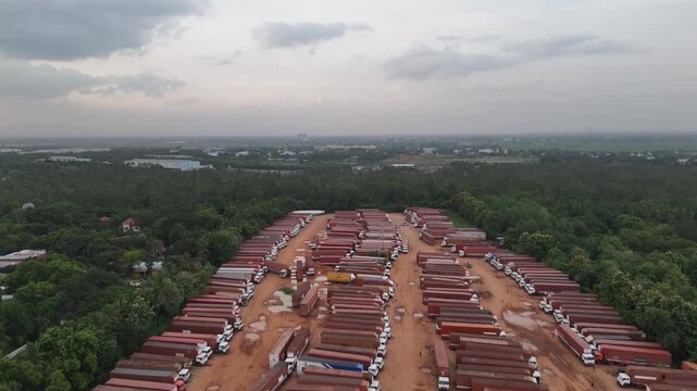 Cinematic drone view of an immense truck staging area with long, neat rows of commercial vehicles parked on dirt. Perfect for freight, transport, and industry.