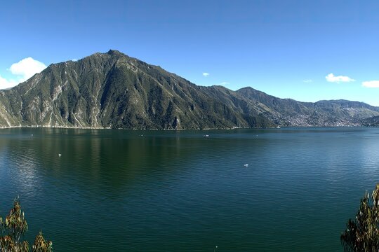 Mountainous lake view with calm water under a bright blue sky