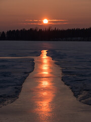 Sunset behind icy path on frozen lake