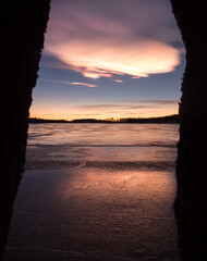 Nacreous cloud in the sky behind frozen lake