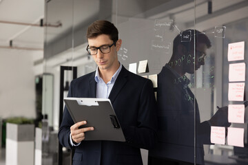 Serious young Latin businessman writing notes in document © fizkes