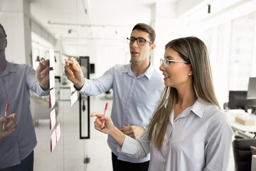 Latin couple of businesspeople planning tasks at glass scrum board