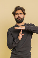 Tired serious upset young Lebanese man showing timeout gesture, limit or stop sign, no pressure, I need more time, relax, break deadline. Indian Hindu guy isolated on studio beige background indoors.