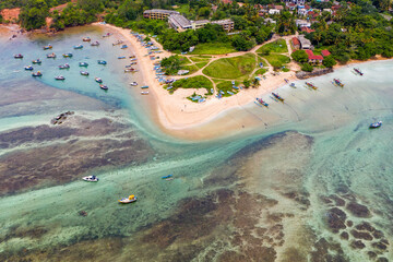 Sri Lanka travel image—Weligama Beach with traditional fishing vessels, ocean waves, and lush palm trees.