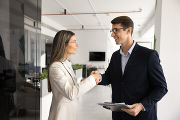 Fototapeta premium Two positive young Latin business colleagues giving handshake