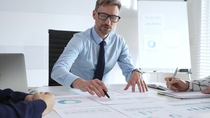 Business professional presenting financial strategy during corporate meeting with colleagues, analyzing charts and discussing data for growth and success planning