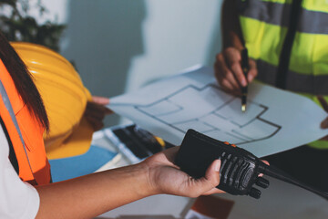 Closeup of team of industrial engineers meeting analyze machinery blueprints consult project on table in manufacturing factory. Working in manufacturing plant or production plant.