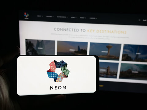 Stuttgart, Germany - 09-29-2025: Person holding smartphone with logo of Saudi Arabian real estate project NEOM on screen in front of website. Focus on phone display.