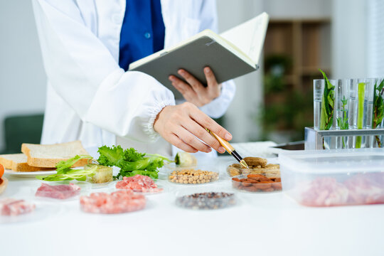 Female nutritionist in lab coat analyzing food and writing in notebook. Healthy eating, organic testing, and nutrition science in a clean lab.