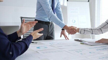 Business partnership success concept with handshake in modern office, financial charts, graphs and laptop on desk representing teamwork, agreement and corporate growth - Powered by Adobe