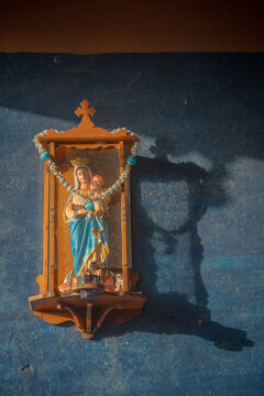 colorful small statue of virgin mary with child in wooden glass display on blue wall in asia