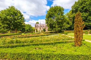 Park landscape with shrubs and flowering plants in public park of TerWorm Castle, leafy trees and castle in background, sunny summer day in Heerlen, South Limburg, Netherlands
