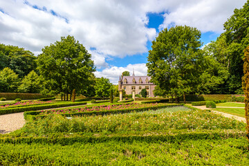 Paths among bushes and flowering plants in public park of TerWorm Castle, green leafy trees and castle standing out in background, sunny summer day in Heerlen, South Limburg, Netherlands