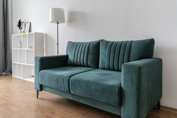 modern interior in the living room with white walls. The room has a blue sofa, gray curtains on the window, shelves and a table.