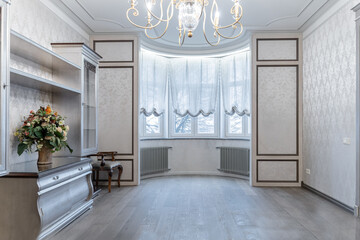 retro interior of large bright living room. Wooden furniture, large chandelier on ceiling, retro chest of drawers. lot of light in room. Illuminated by lamp. Architecture inside home