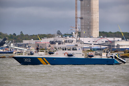Swedish Coast Guard patrol boat J02 navigating through the Karlskrona archipelago with the NKF cable factory, reflecting Baltic Sea maritime security