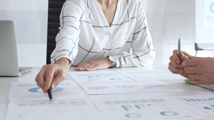Business team analyzing financial charts and data reports during strategy meeting, hands pointing to documents on table with graphs and diagrams for planning - Powered by Adobe