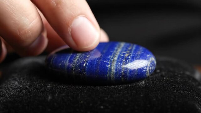 Examining a Piece of Polished Lapis Lazuli on Black Velvet at Close Range