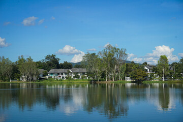 Fototapeta premium Tranquil view of modern, luxury residential homes situated along the shoreline of a calm lake or pond under a clear blue sky
