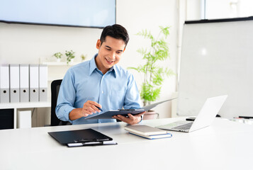 Obraz premium Young man businessman accountant looks at the papers reviews documents, business agreements, bills at desk in the office.