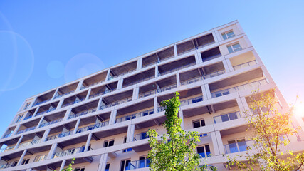 A residential building  by lush green trees and surrounded by  fresh vegetation on a clear sunny day. Modern architecture residential apartment building complex surrounded by greenery.